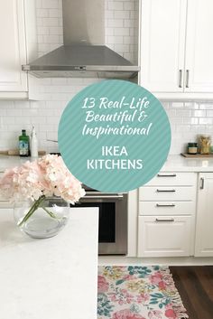 a kitchen with white cabinets and pink flowers in a vase on the counter top next to an oven