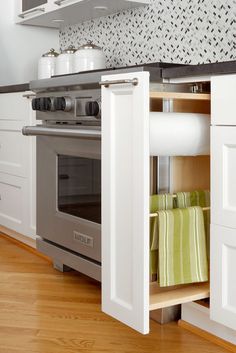 a kitchen with white cabinets and an open oven door in the center is filled with dishes