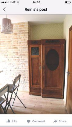 a wooden cabinet sitting in the middle of a room next to a table and chairs