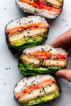 someone is holding up some sushi rolls with different toppings on top of it