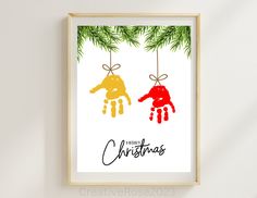 a christmas card with two hand prints hanging from a pine tree branch and the words merry christmas