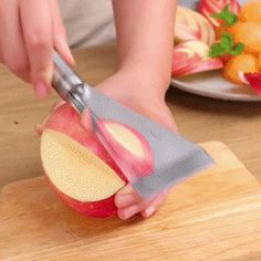 a person cutting an apple on top of a wooden cutting board with a large knife