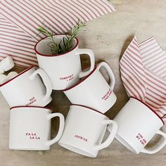 five coffee mugs sitting next to each other on top of a table with red and white striped napkins