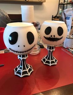 two glasses that have been painted to look like jack and sally faces on them, sitting on a table