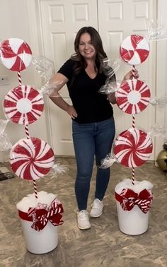 a woman standing in front of two buckets filled with candy canes and marshmallows