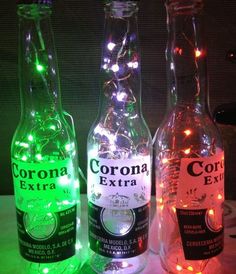 three bottles with lights in them sitting on a table