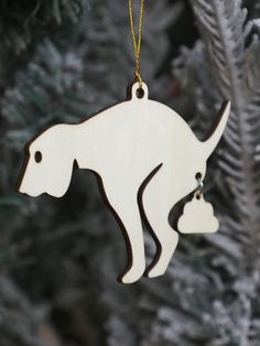 a white ornament hanging from a christmas tree with a dog on it's back