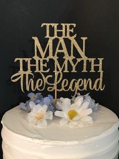 a white cake with blue flowers and the words the man, the legend on it