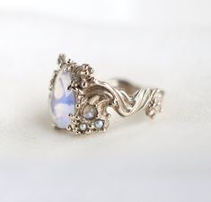 a white ring with a blue stone surrounded by filigrees