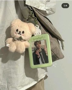 a teddy bear is attached to a keychain that has a photo on it