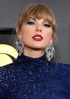 taylor swift at the golden globe awards wearing red lipstick and blue eyeshadow with diamond earrings