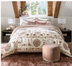 a bedroom with a bed, ottoman and window in the corner that has a pink rug on it