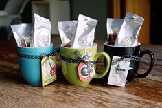 three coffee mugs with different types of tea bags in them sitting on a table