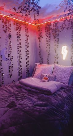 a bed in a room with purple sheets and lights on the wall above it is a teddy bear