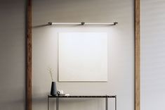 a table with two vases on it in front of a white wall and wooden frame