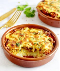 two brown bowls filled with lasagna casserole on top of a white table