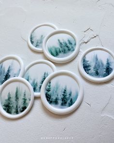 four coasters with trees painted on them