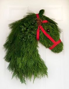 a horse head made out of grass and red ribbon on the front door to decorate it