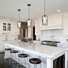 a large kitchen with white cabinets and marble counter tops, an island with four stools