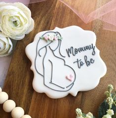 a decorated cookie with the words mommy to be on it next to flowers and pearls