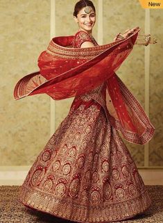 a woman in a red and gold lehenga poses for the camera with her hands on her hips