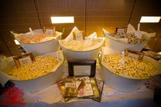 there are many different types of popcorn on the table and in buckets for sale