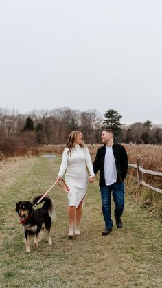 a man and woman holding hands while walking their dog