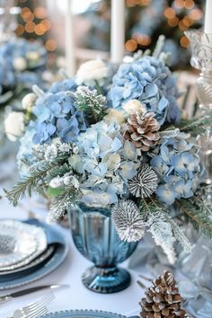 a blue vase filled with flowers sitting on top of a table next to plates and silverware