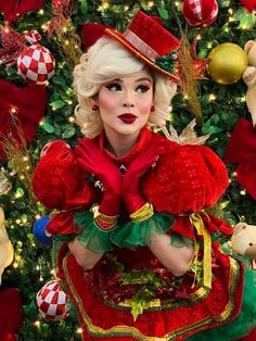 a woman dressed in red and green posing for the camera with christmas decorations around her