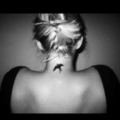 a woman with a bird tattoo on her back neck and behind her head is a black - and - white photo