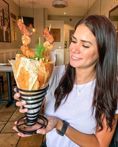 a woman holding up a cup filled with food