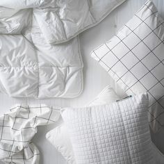 pillows and blankets laid out on a bed with white comforter, pillow case, and blanket