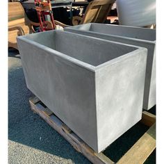 two cement planters sitting next to each other on a pallet in the sun