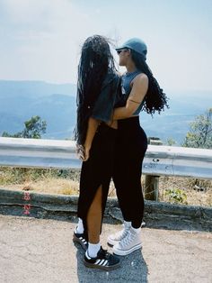 two women standing on top of a hill with their arms around each other's backs