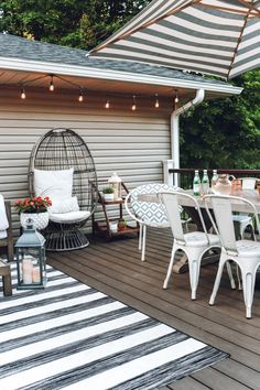 an outdoor patio with white furniture and striped rugs on the wooden decking area