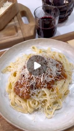 a white plate topped with pasta covered in sauce and grated parmesan cheese