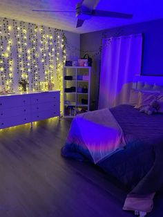 a bed room with a neatly made bed and purple lights on the wall behind it