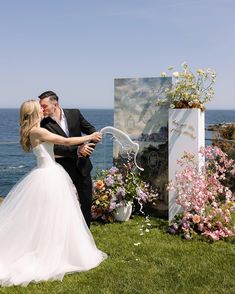 a bride and groom are standing in front of an easel with flowers on it