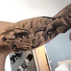 a man with a tattoo on his arm that has the creation of jesus's hands