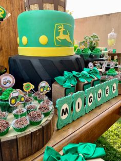 a table topped with lots of cupcakes covered in green frosting and decorations