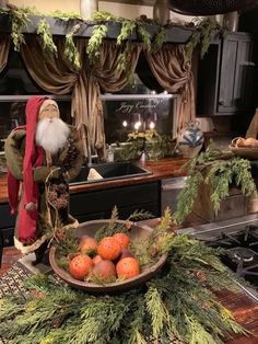 a santa clause standing next to a bowl of fruit on a kitchen counter with greenery