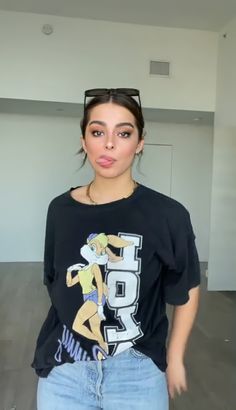 a young woman wearing a black shirt and jean shorts is making a funny face while standing in an empty room