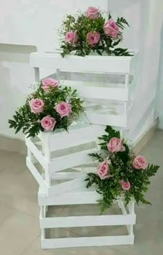 three white planters with pink roses in them on top of each other next to a wall