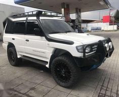 a white suv parked in front of a gas station with black rims and tires