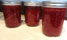 four jars filled with jam sitting on top of a table