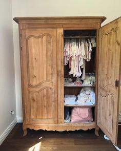 a wooden armoire with clothes hanging on it