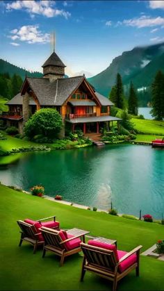 two lawn chairs sitting on top of a lush green field next to a body of water