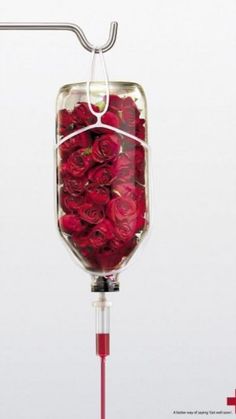 a glass filled with lots of pink flowers on top of a metal rod in front of a white wall