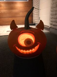 a carved pumpkin with an evil face on it's head and horns is lit up