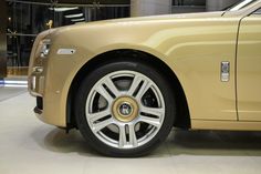 a gold rolls royce parked in front of a building